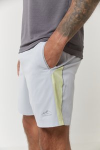 Lys grå treningsshorts med en glatt tekstur og sidelomme, med en lys grønn aksent og en logo trykket nær kanten.