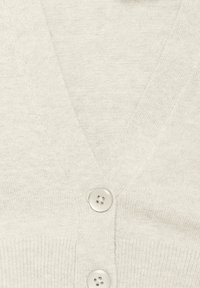 Vaaleanbeige neuletakki pehmeästä kankaasta, jossa on V-pääntie, kolme nappia edessä ja ribbikaulusreunat.