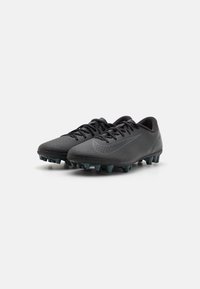 Black soccer cleats with a textured synthetic upper, pointed toe, matching laces, and a greenish outsole featuring multi-directional studs.