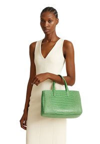 Borsa a mano in pelle verde con decorazione a forma di coccodrillo, dalla forma strutturata, con doppio manico e superficie liscia. Design leggero e compatto.