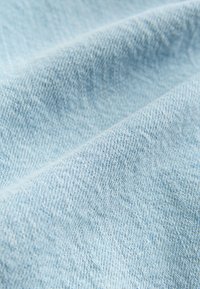 Tessuto di denim azzurro chiaro con una trama diagonale e sottili variazioni di tonalità, dalla texture morbida.