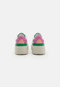 Vastag talpú sneaker, fehér bőr felső réteggel, zöld, rózsaszín és őszibarack színű részletekkel, texturált sarokkal és bézs platform talppal.