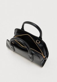 Sac à main en cuir noir avec deux poignées, fermeture éclair dorée partiellement ouverte, et détail en anneau doré sur un fond clair.