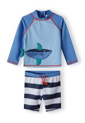 Ensemble de bain bleu avec un haut à manches longues arborant un motif de requin et des accents rouges. Short assorti avec des rayures horizontales bleu marine et blanches.