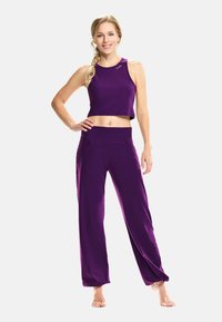 Fialový športový crop top a zodpovedajúce široké nohavice, vyrobené z mäkkého materiálu, s priliehajúcim pásom a voľným dizajnom.