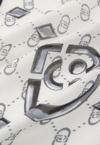 Tessuto a fantasia con sfondo bianco caratterizzato da forme geometriche nere e grigie, inclusi motivi a catena e a rombo, con una finitura testurizzata.