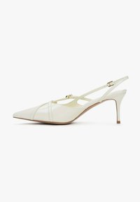 Escarpin slingback en cuir verni blanc à talon haut, bout pointu, fines brides et détail de boucle dorée sur un fond blanc épuré.