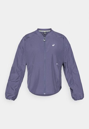 Giacca leggera viola con colletto alto, chiusura a zip completa e polsini elasticizzati. Presenta tasche laterali e un logo sul petto.