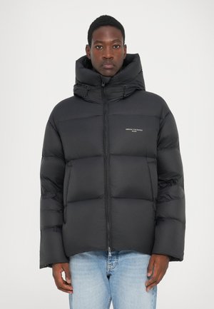 Schwarze Pufferjacke mit hohem Kragen, Reißverschluss und verstellbarem Kapuze. Verfügt über eine gesteppte Polsterung und ein Logo auf der Brust.