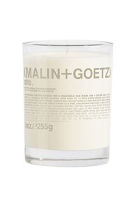 Duftkerze in einem klaren Glasbehälter. Weißes Wachs sichtbar mit einem Baumwolldocht. Das Etikett zeigt grauen Text mit Produktdetails und Branding.