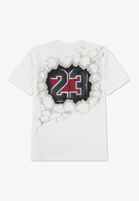 Λευκό βαμβακερό T-shirt με γραφικό σχέδιο του αριθμού "23" σε μαύρο και κόκκινο, με εφέ ραγισμένου τοίχου γύρω του.