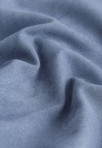 Tissu en daim bleu doux avec des plis subtils et une surface légèrement texturée en vue rapprochée.
