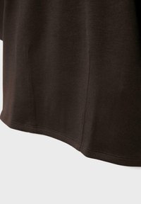 Mørkebrunt stof med lodrette sømdetaljer og en lige syet kant, vist mod en hvid baggrund.