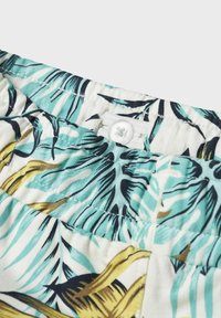 Pantaloni shorts con motivo tropicale, caratterizzati da foglie di palma verdi e gialle su uno sfondo chiaro, con chiusura a bottone bianco in vita.