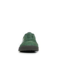 Sneaker verde in suede con punta rotonda, suola in gomma nera e lacci verdi. Presenta accenti laterali bianchi e una superficie superiore testurizzata.
