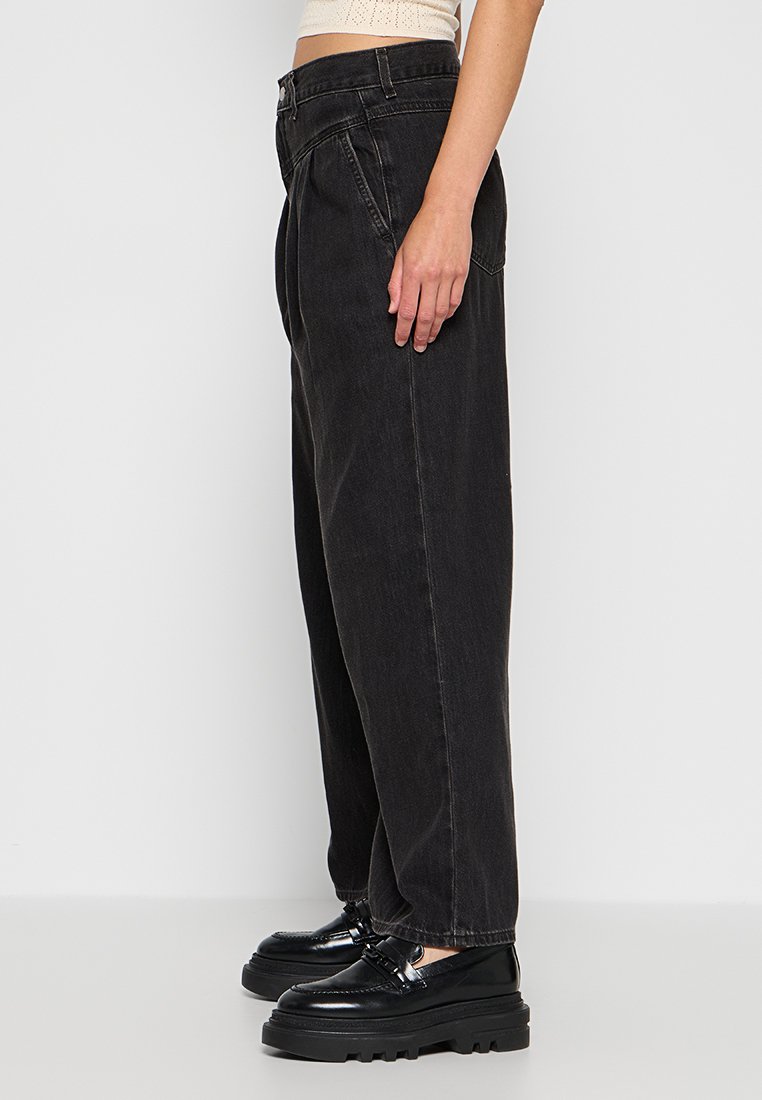 Pantalons en denim noir à jambe large avec une taille haute, dotés d'une fermeture éclair à l'avant, de poches latérales et d'une coupe décontractée. Tissu texturé avec un léger délavage.