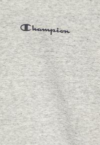Felpa in tessuto di cotone grigio con una texture morbida, caratterizzata dal logo "Champion" nero sulla parte superiore sinistra.
