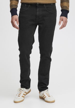 Sorte denim jeans med slim fit, med fem lommer, diskrete slidser og en standard knap-gennemsnitslukning. Parret med hvide sneakers.