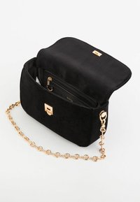 Czarna torebka z zamszowej skóry z złotym łańcuszkiem, z magnetycznym zapięciem klapki i wewnętrzną kieszenią na zamek. Charakteryzuje się prostym prostokątnym kształtem.