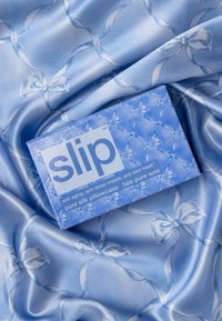 Seidenkissenbezug in Hellblau mit glatter Textur und einem wiederholten Schleifenmuster. Inklusive Boxverpackung mit der Marke "slip."