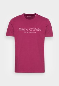 Fuchsia bomulds t-shirt med rund hals og korte ærmer. Har "Marc O'Polo" og "EST. I STOCKHOLM" trykt i hvid tekst.