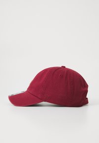 Maroon baseball cap made of cotton with a curved brim, embroidered logo near the front, and adjustable strap at the back.