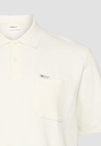 Polo à manches courtes blanches texturées avec deux boutons, une poche poitrine étiquetée "Elevated Casual" et une étiquette de la marque s.Oliver à l'intérieur du col.
