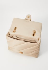 Μπεζ κεντητή τσάντα ώμου με χρυσές λεπτομέρειες, διαθέτει μαγνητική κλείσιμο, εσωτερική τσέπη με φερμουάρ και λεία, απαλή υφή.