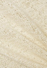 Gebreide stof in een lichte crème kleur met een gestructureerde, open weving. Kenmerkt zich door een zachte, iets glanzende oppervlakte en subtiele variaties in draaddikte.