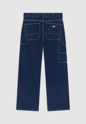 Donkerblauwe denim werkbroek met wijde pijpen, twee grote achterzakken, zijvak voor gereedschap en een rood merkembleem op de rechterachterzak.
