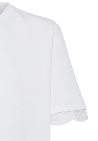 Chemise blanche à manches courtes avec encolure ronde et détail de bordure en dentelle aux extrémités des manches, vue en angle du haut du buste.