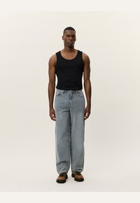 Black tank top, light blue wide-leg jeans, and brown boots. The jeans feature a high waist and classic five-pocket design.