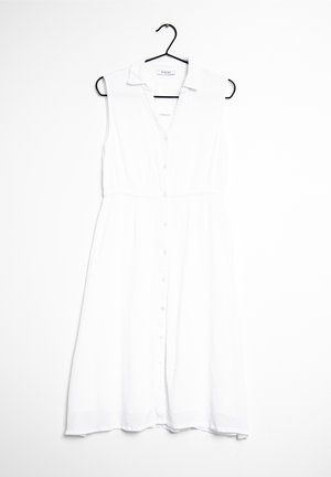 Biała sukienka bez rękawów z kołnierzykiem, z zapięciem na guziki z przodu i w talii, wykonana z lekkiego materiału. Gładka faktura, do kolan.