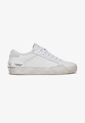 Baskets blanches en cuir et daim, avec un design bas, un bout rond, des lacets plats et une semelle en caoutchouc texturé.