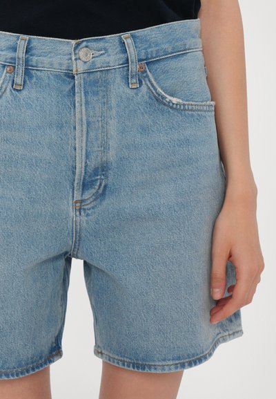 Ανοιχτό μπλε τζιν σορτς με ψηλή μέση, σκισμένο τελείωμα και έξι τσέπες. Διαθέτει μεταλλικά στοιχεία σε χαλκοκόκκινο χρώμα και ραμμένες λεπτομέρειες.