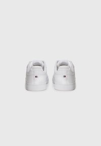 Sneakers bianchi con una finitura in pelle liscia, forma arrotondata e design a profilo basso. Presentano cuciture minimaliste e un piccolo logo sul tallone.
