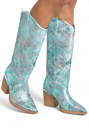 Botas de serpiente en azul y plata con punta afilada, altura hasta la mitad de la pantorrilla y un tacón de bloque de madera. Costuras blancas que realzan el diseño.