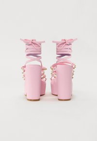 Rosa høyhælede sandaler med solid plattform, spiral-snøring og gullnitter på sidene. Glatt materiale og blokkheledesign.