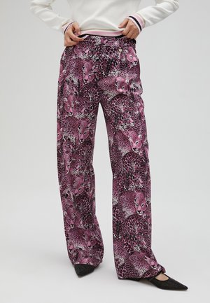 Wide-leg pants featuring a vibrant pink leopard print on soft fabric, with an elastic waistband and black pointed-toe shoes.