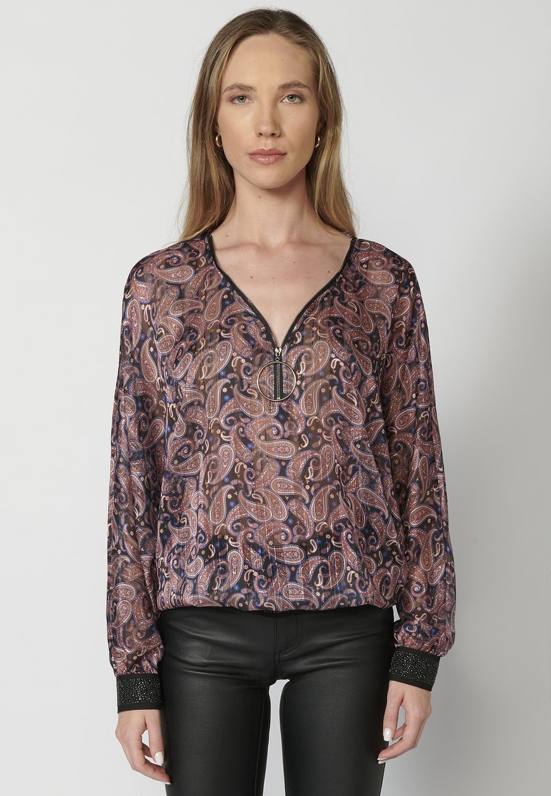 Langärmlige Bluse aus transparentem Stoff mit einem Paisleymuster in dunklen Tönen, ausgestattet mit einem Reißverschluss am Halsausschnitt und strukturierten schwarzen Ärmelbündchen.