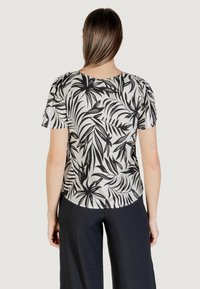 Top a maniche corte con motivo di foglie tropicali bianche e nere, realizzato in tessuto leggero, con scollo rotondo e vestibilità comoda.