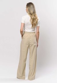 Beiget leveälahkeiset housut, joissa on joustava vyötärönauha. Valmistettu kevyestä materiaalista, takataskulla ja sileällä pinnalla.