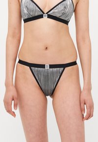 Metallinho hopeapintainen bikinitoppi, jossa on poimutettu rakenne ja musta reunus, jossa on brändätty merkki keskellä. Yhdistetty vastaavilla hopeapintaisilla thong-pohjilla.