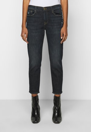 Dunkelblaue Denim-Jeans mit geradem Schnitt und leichten Abnutzungserscheinungen an den vorderen Taschen. Umschlag-Saum und getragen mit schwarzen, hohen Ankle-Boots.