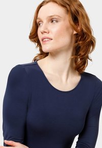 Námořnický modrý top s dlouhým rukávem, kulatým výstřihem a hladkým, pružným materiálem, s minimálním prošitím na ramenou.