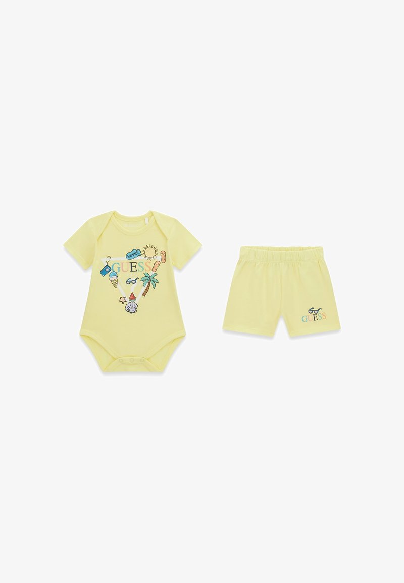 Żółty dziecięcy body i dopasowane spodenki z letnimi motywami graficznymi, w tym słońce, lody, palma i napis "GUESS".