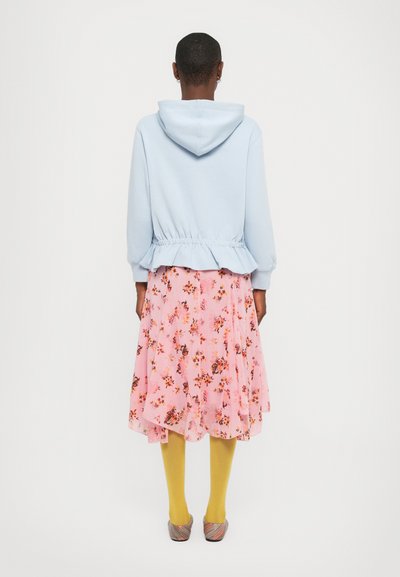 Light blue hooded sweatshirt with elastic waistband paired with a pink floral skirt, yellow tights, and colorful slip-on shoes.