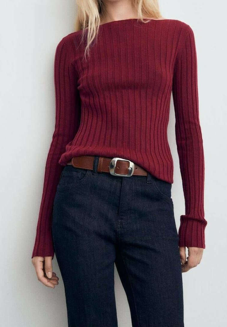Femme portant un haut côtelé bordeaux ajusté à manches longues, rentré dans un jean bleu foncé avec une ceinture marron et une boucle argentée.