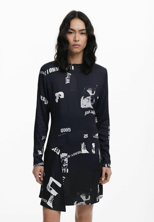 Langärmliges Kleid aus dunkelblauem Stoff mit abstrakten schwarz-weißem Text und grafischen Mustern, mit figurbetontem Schnitt und asymmetrischem Saum.