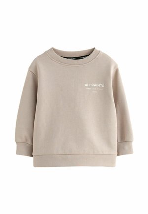 Bežs treniņjak ar ribotām apkaklītēm un piedurknēm. Priekšpusē ir balts logo. Izgatavots no mīksta, gluda auduma. Brīvi pieguļoša dizaina.